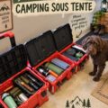 Un camp en pleine nature avec une tente bien installée et des accessoires de camping autour.